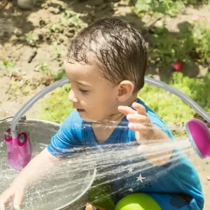 شست شوی صورت کودک با دوش شارژی در فضای باز